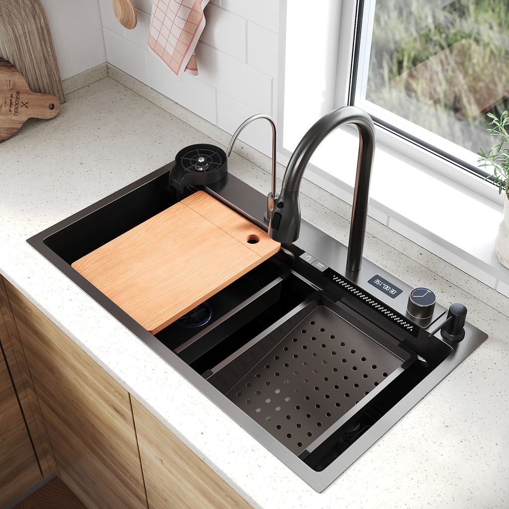 A modern kitchen sink with accessories, set against a window with greenery outside.