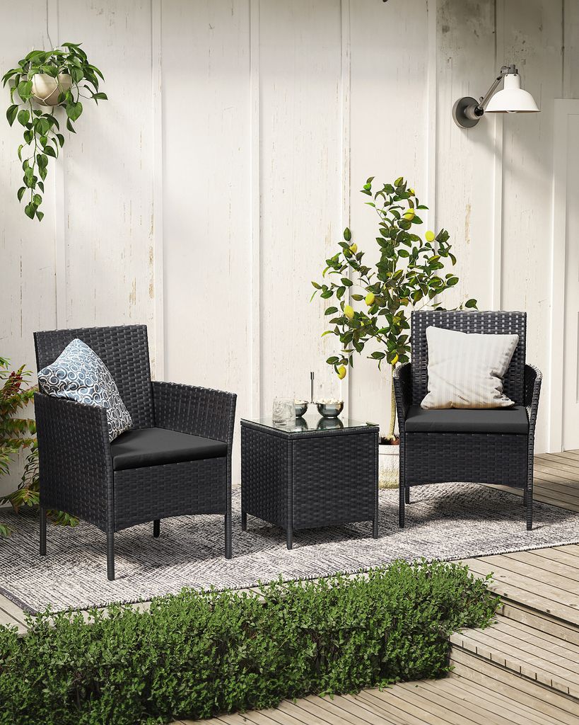 A black rattan furniture set with two chairs and a table on a patio.
