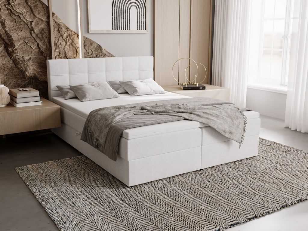 A bedroom setting with a white upholstered bed as the main focus, styled with bedding and a rug.