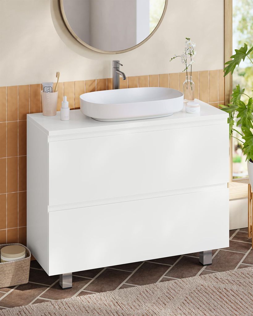 A white bathroom vanity with a sink and faucet, set against a tiled wall.