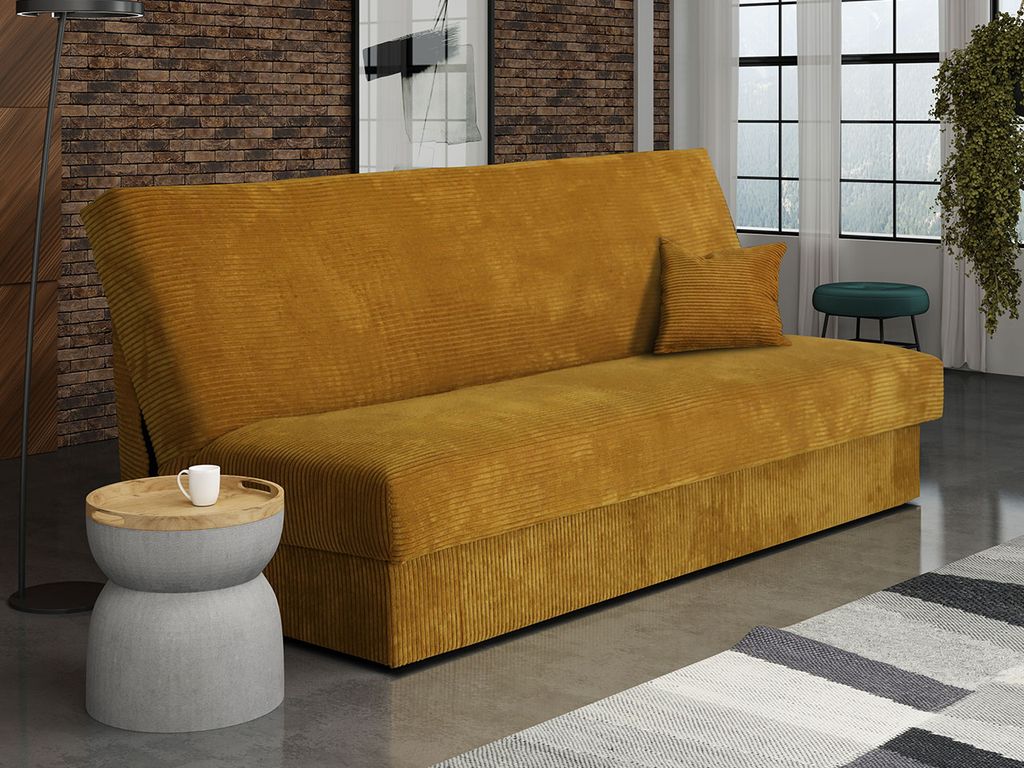 A mustard yellow sofa bed is shown in a living room setting with a small side table and a rug.