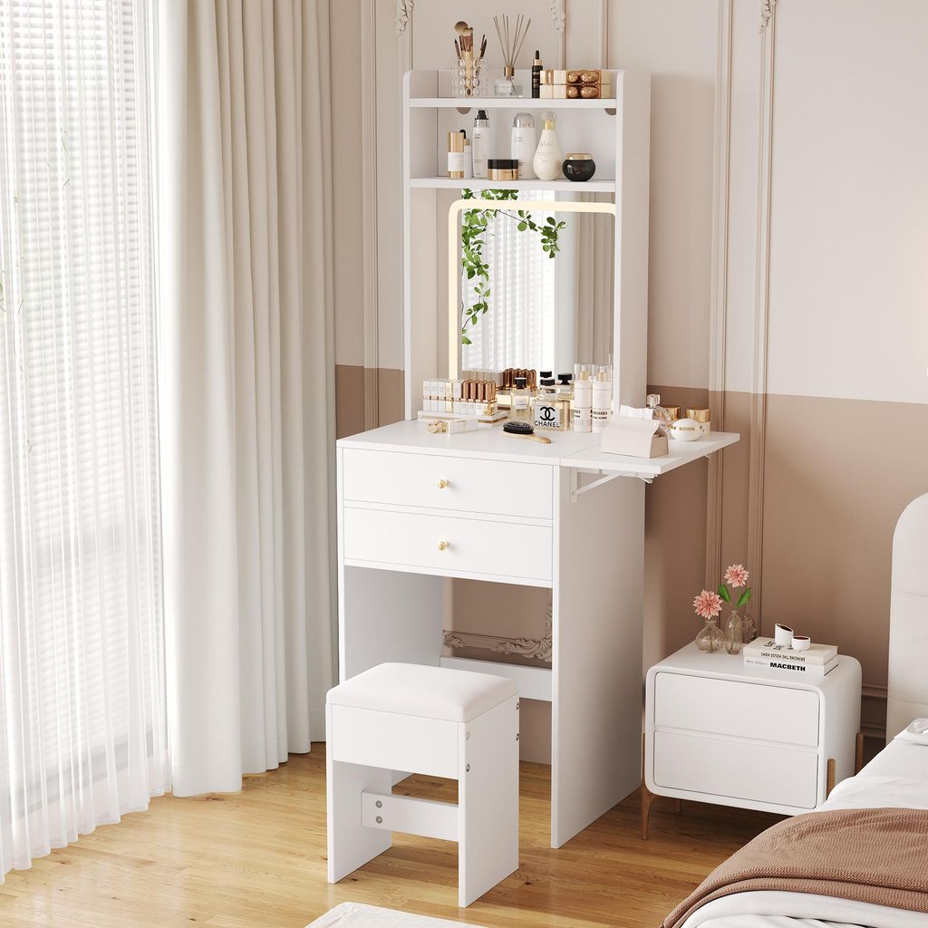 A white vanity table with a mirror and stool, set up in a bedroom next to a window and a nightstand.