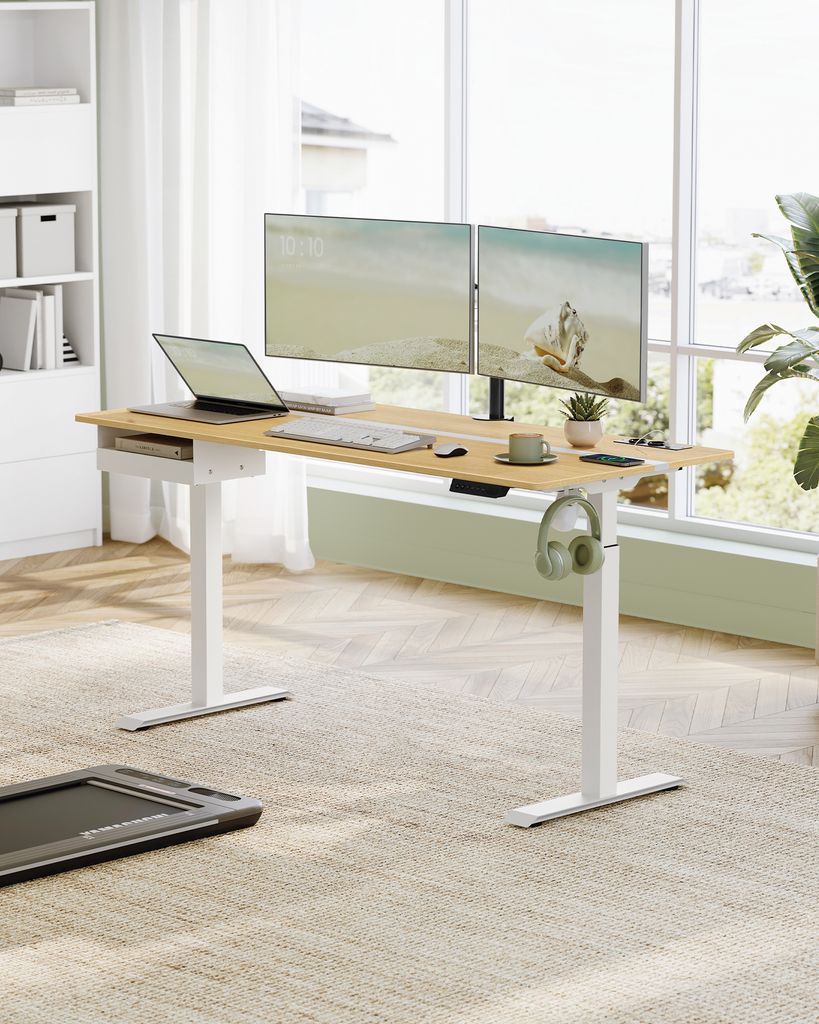 A standing desk setup in a bright room with large windows.