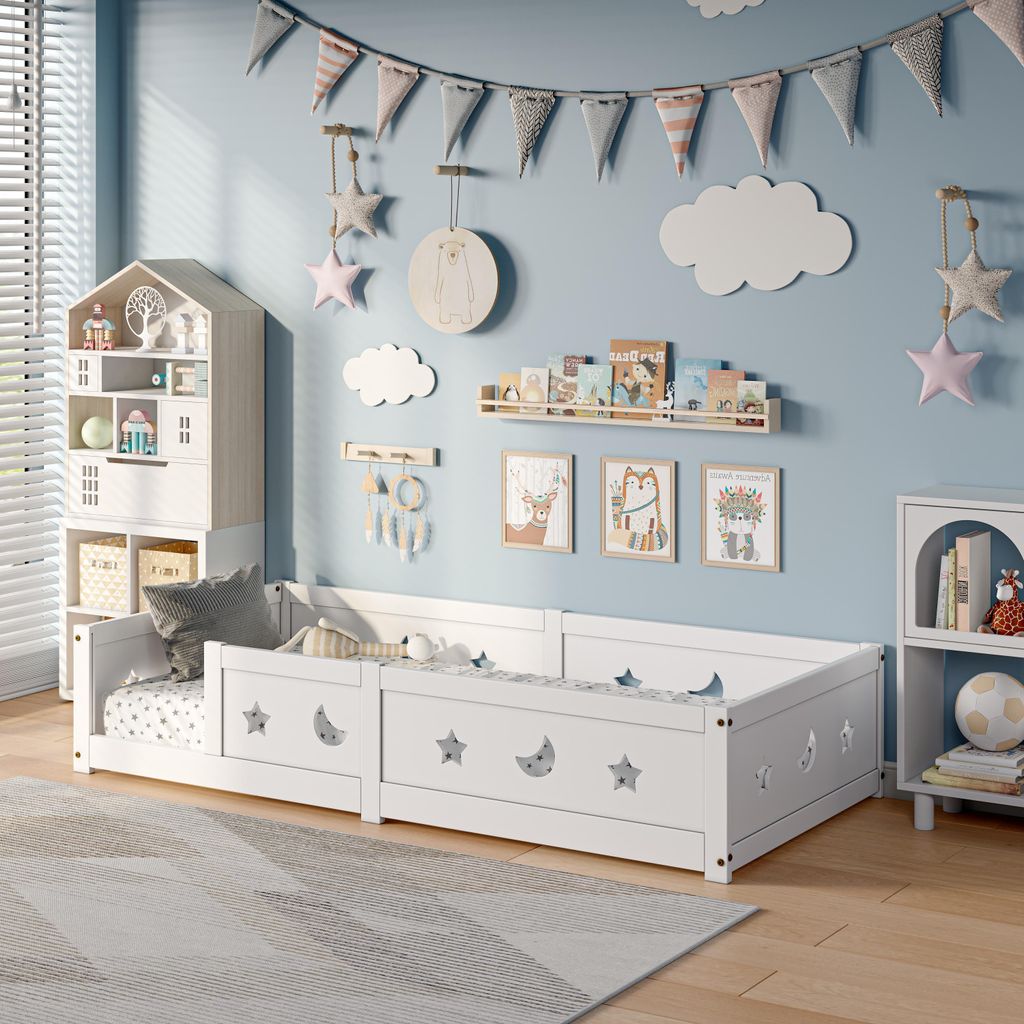 A child's bedroom with a white bed, decorated with stars and moons, and various wall decorations.