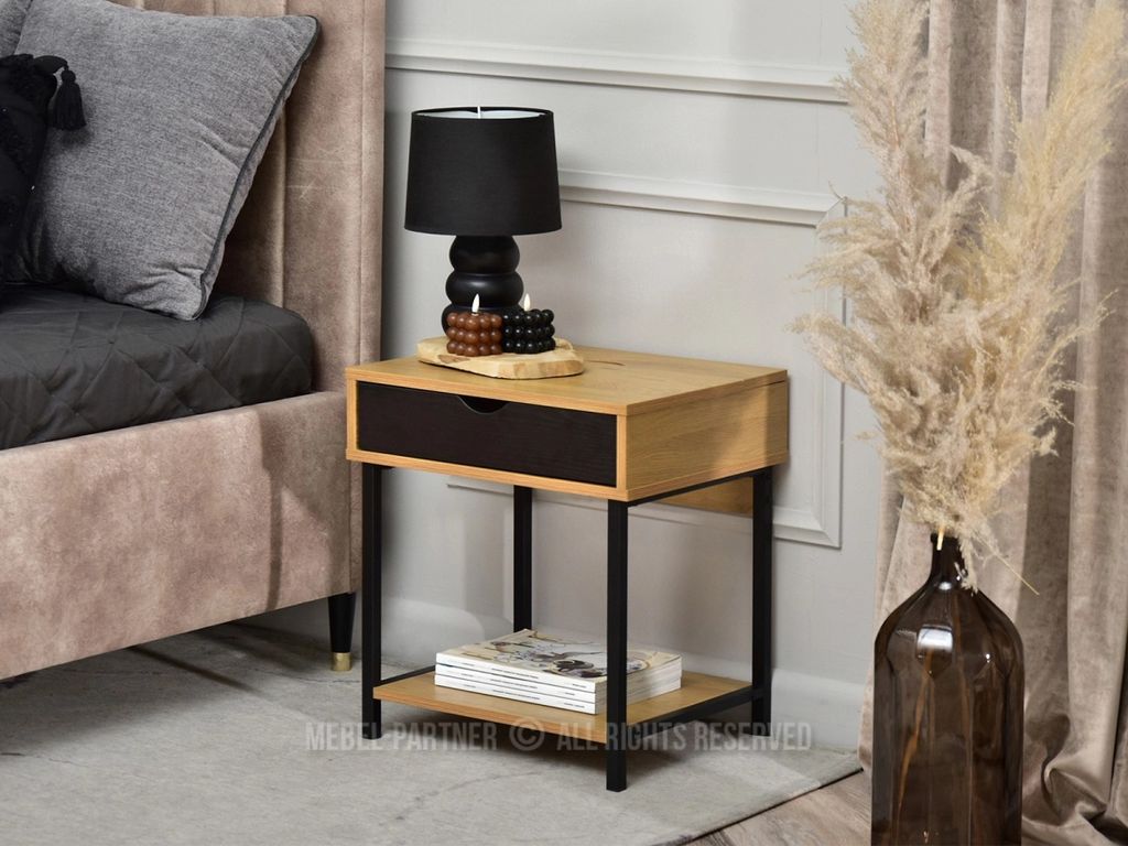 A bedside table next to a bed, with a lamp and decorative items on top.
