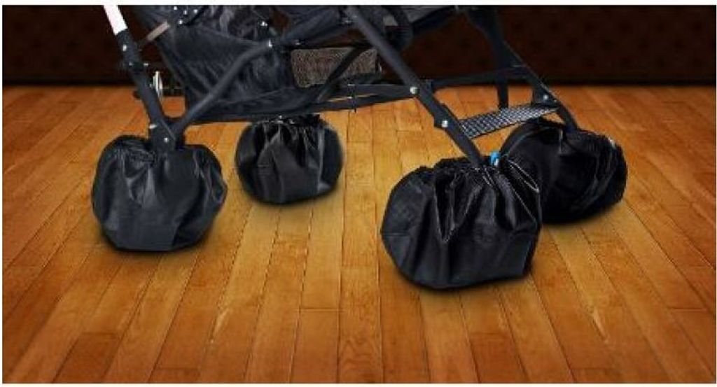 A close-up view of a stroller's wheels covered with black protective bags, resting on a wooden floor.