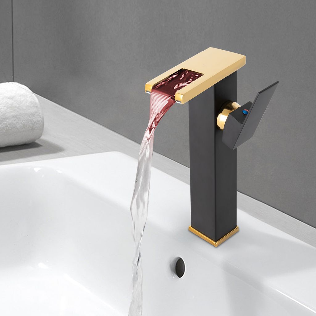 A modern black and gold waterfall faucet with LED lighting is shown in use over a white sink.