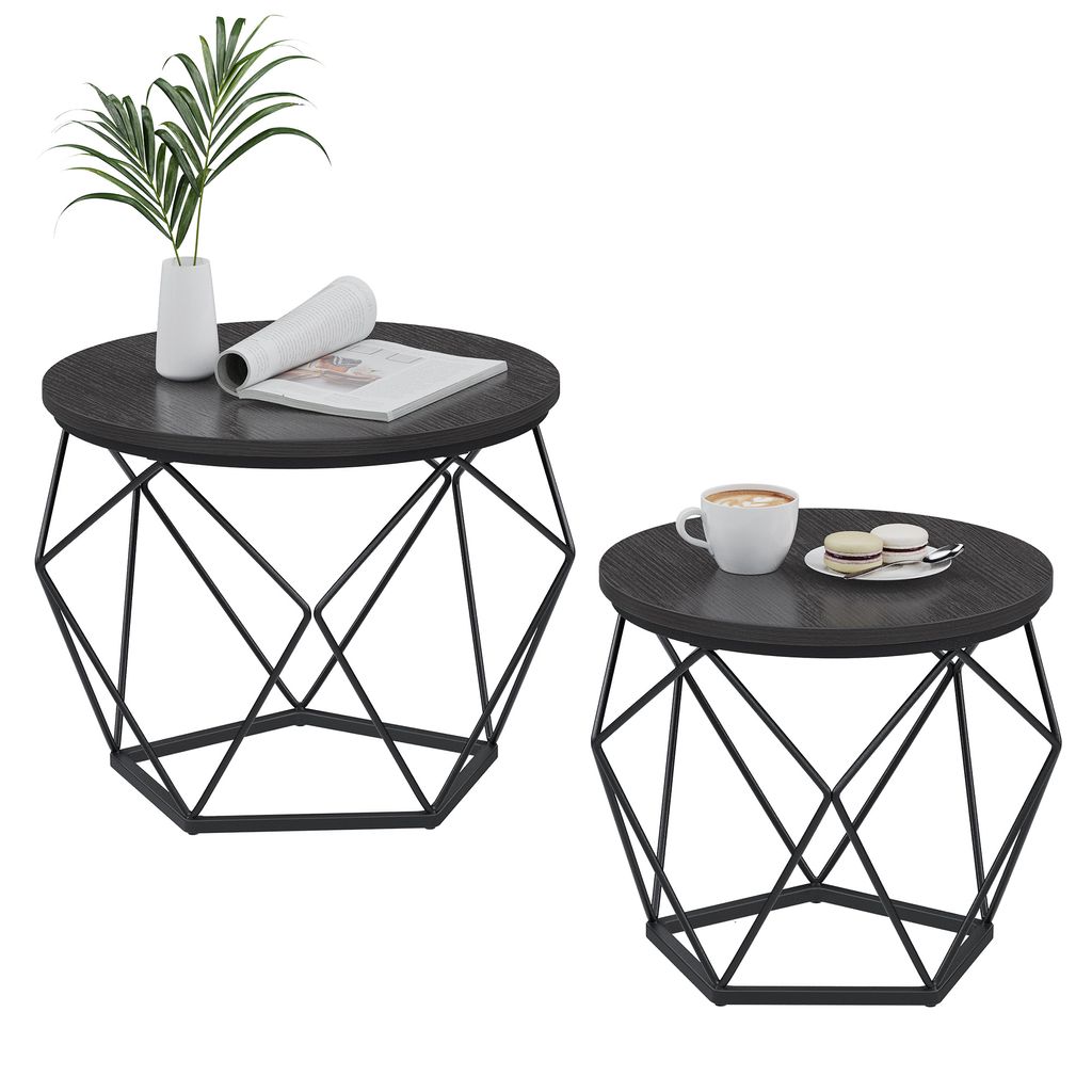 Two round coffee tables with geometric metal bases and dark wood tops, one set with a plant and book, the other with a coffee cup and macarons.