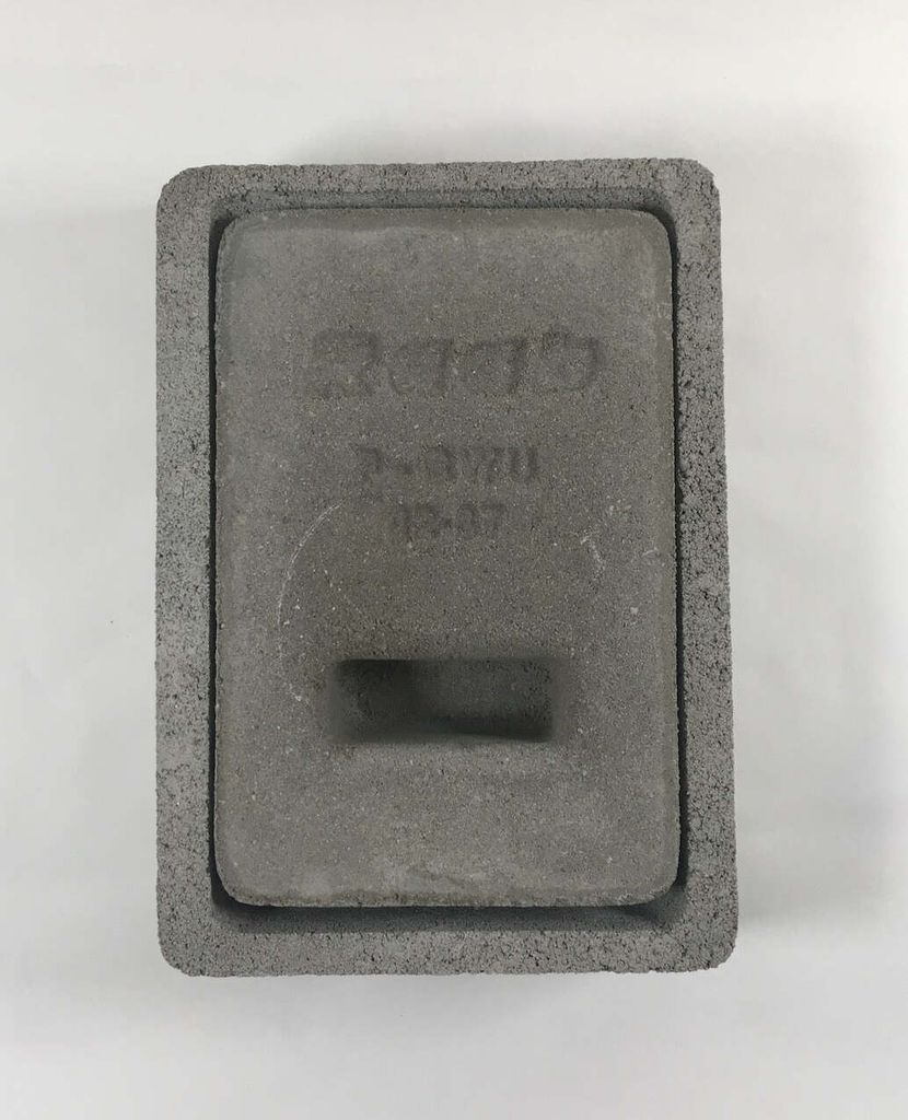 A close-up, top-down view of a gray concrete chimney flap with embossed text.