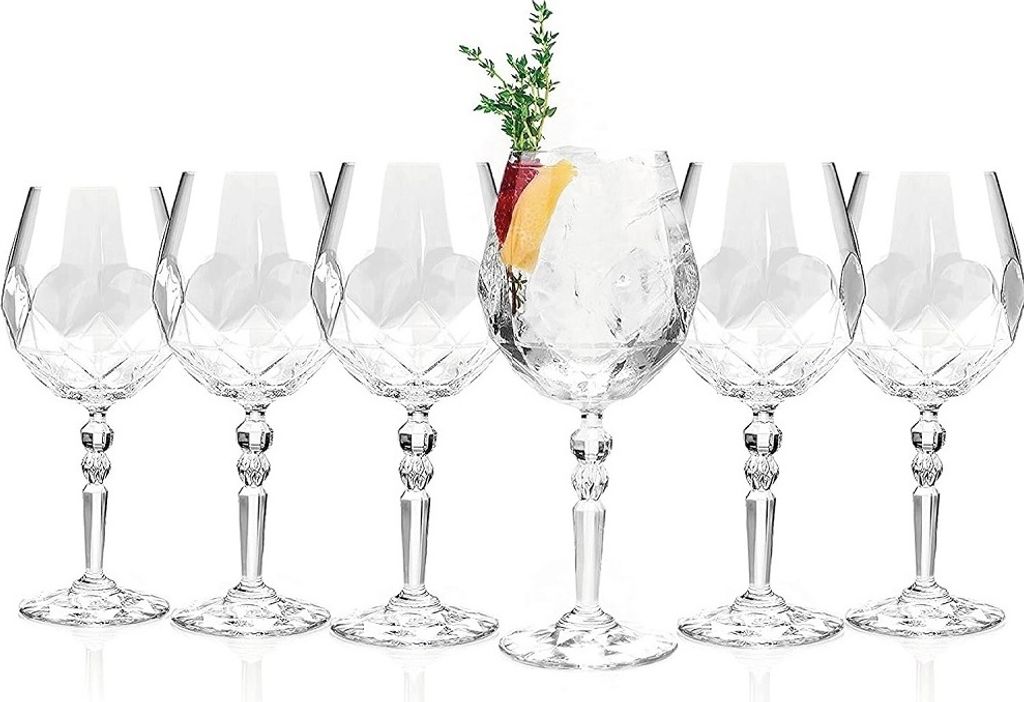 A set of six crystal cocktail glasses, with one glass filled with ice, fruit slices, and a sprig of greenery.