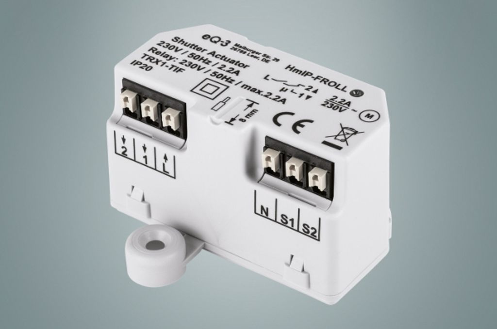 A white electronic device with labels and connectors, set against a plain gray background.