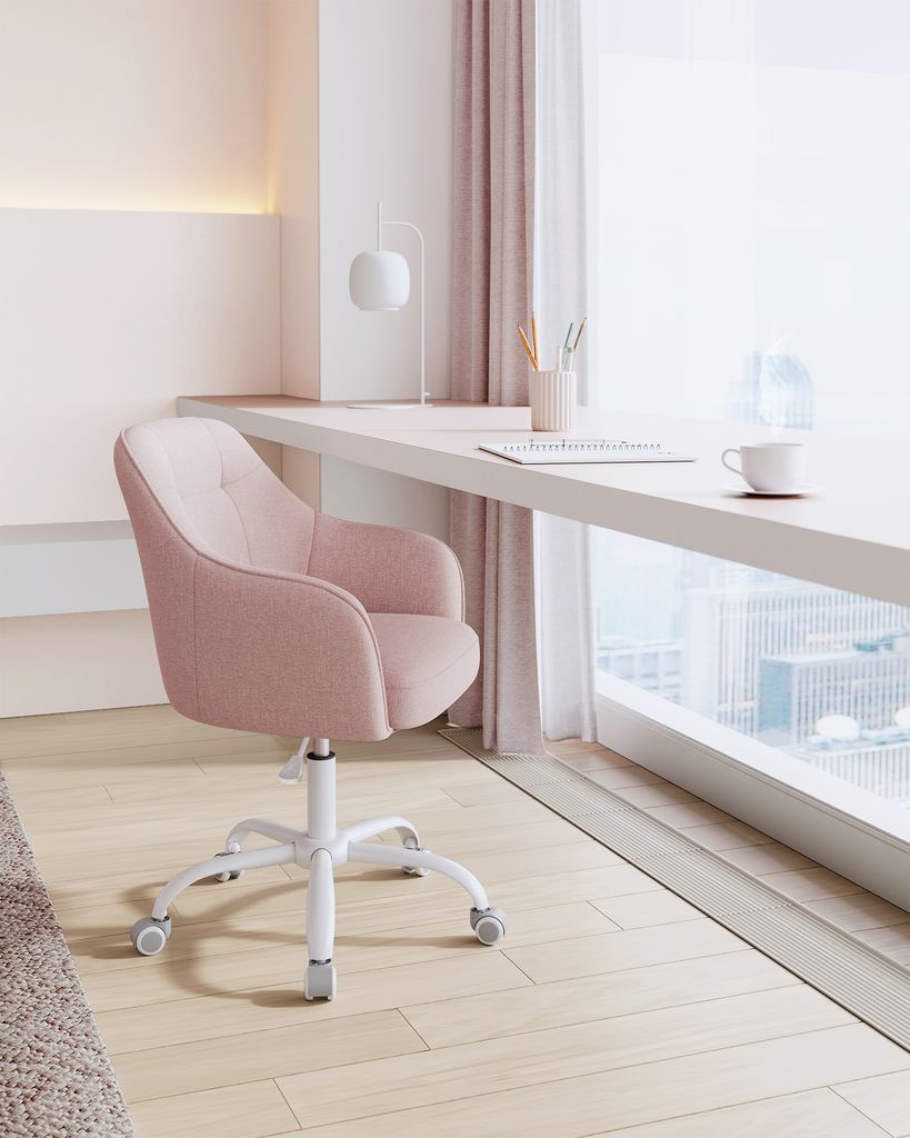 A pink office chair in front of a desk by a window.