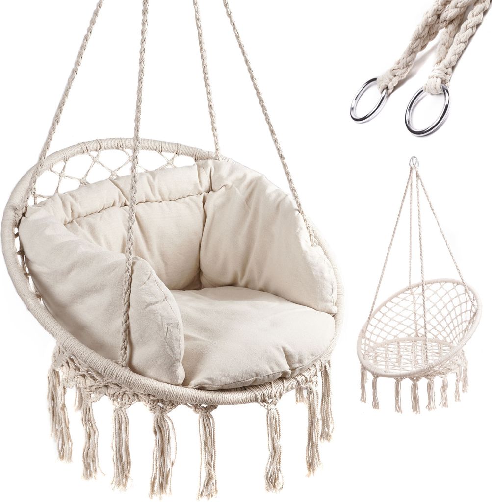 A macrame hanging chair with a cushion and tassels, shown on a white background. A smaller, empty macrame chair is shown in the background, along with metal rings and rope.