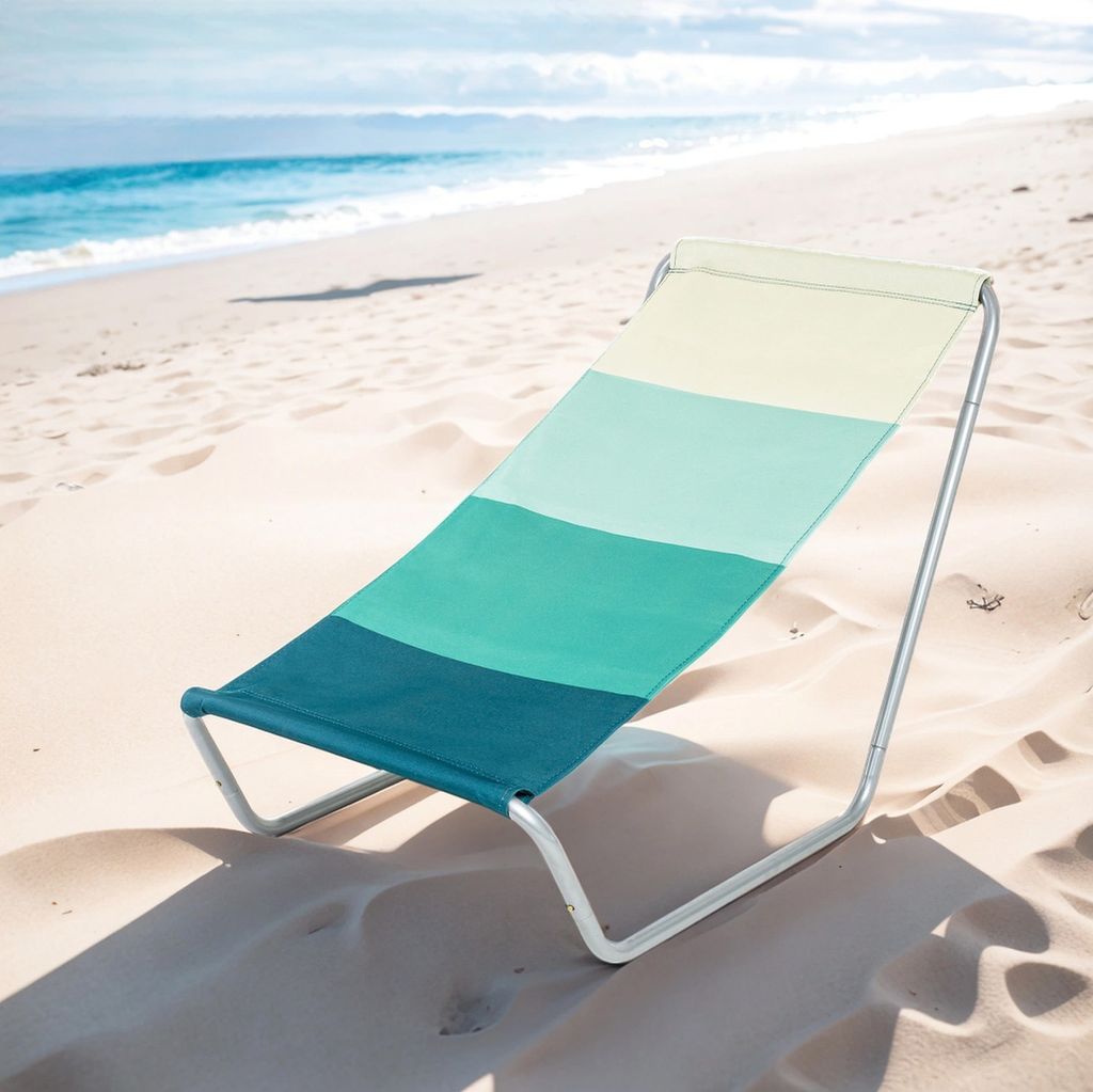 A striped beach chair on a sandy beach with the ocean in the background.
