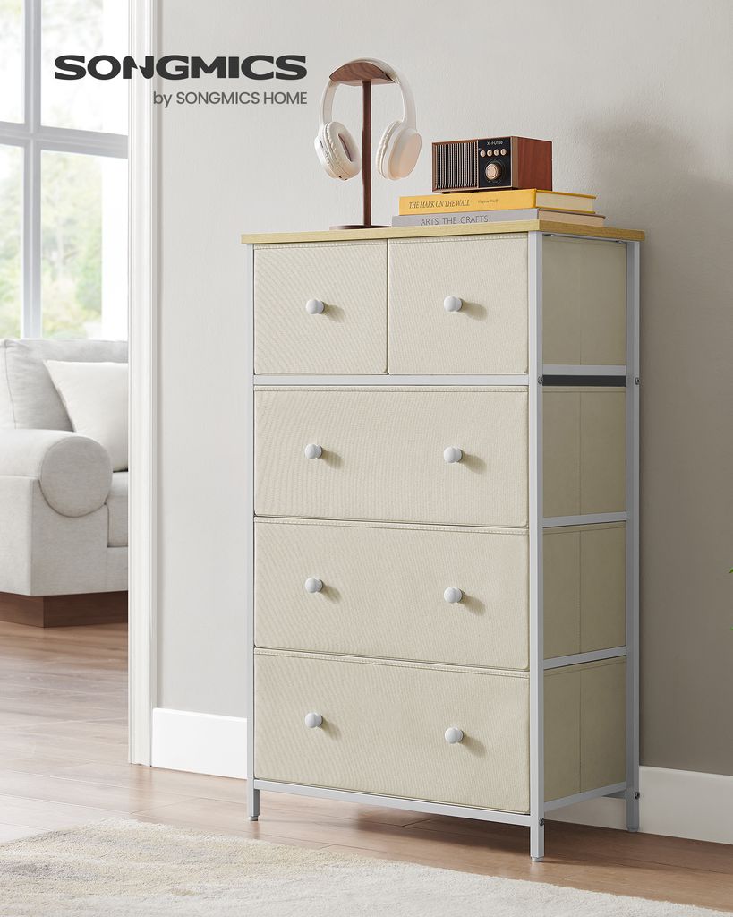A beige fabric dresser with 5 drawers stands in a well-lit room next to a doorway and a couch. A pair of headphones and a vintage-style radio are on top.