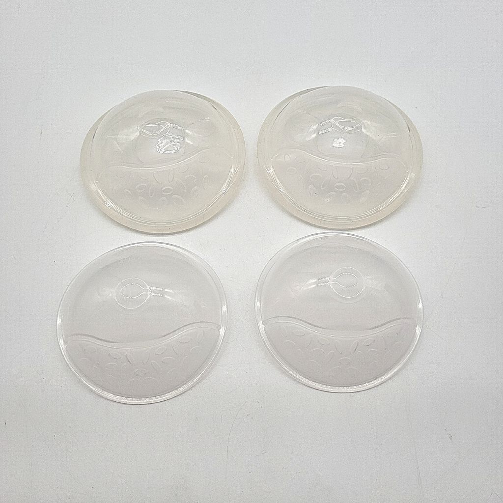 Four clear plastic breast shells are arranged in a two-by-two grid on a white background.