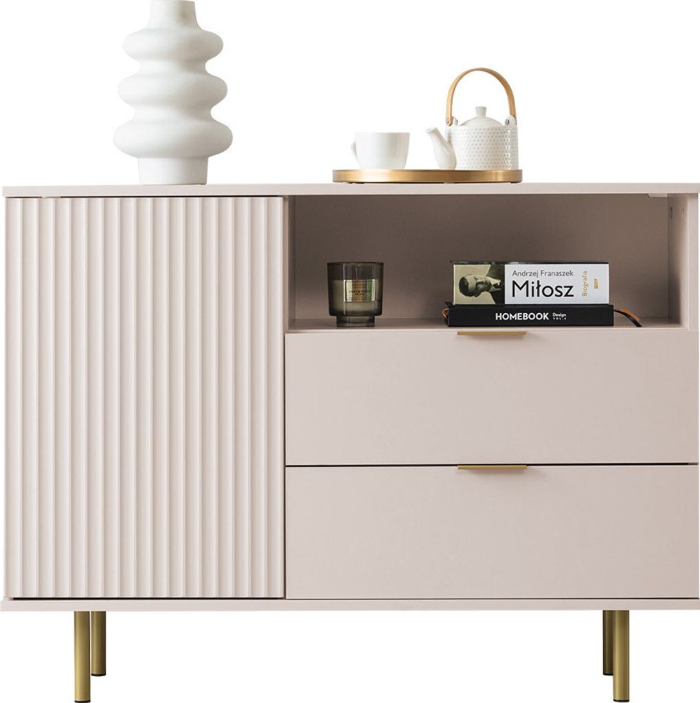 A light pink cabinet with fluted doors and drawers, decorated with a white vase and a teapot on top.