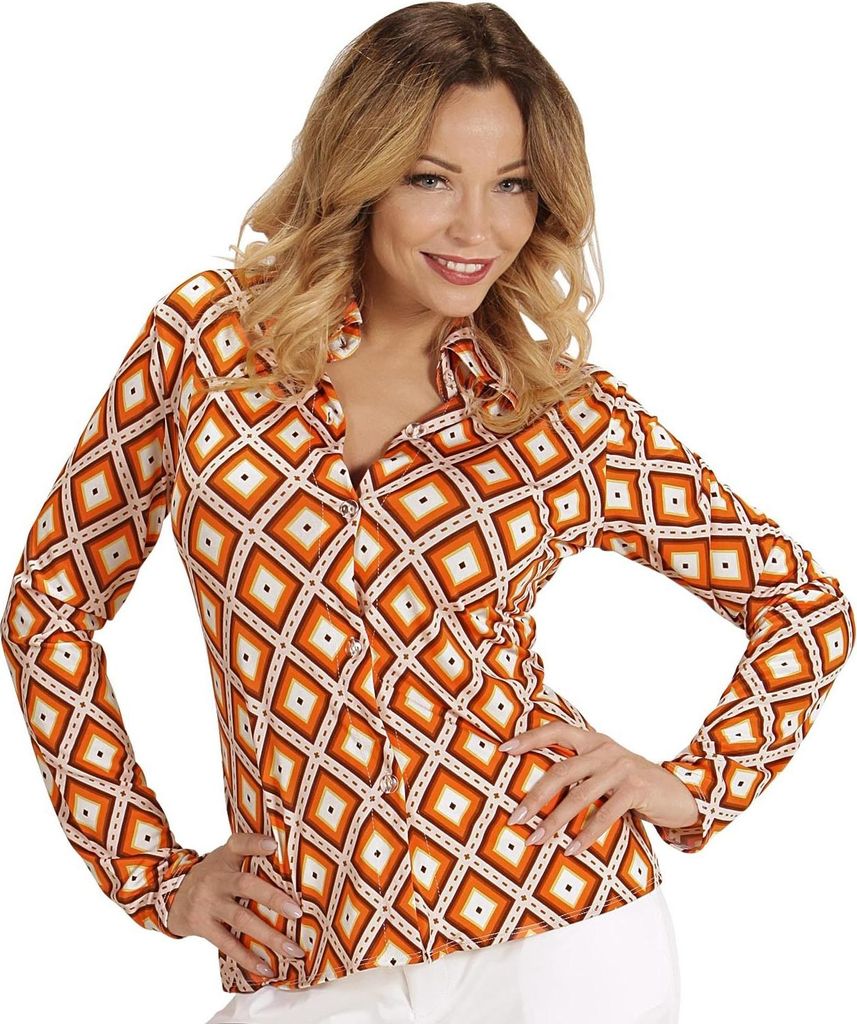 A woman is posing in a studio setting wearing a patterned blouse.