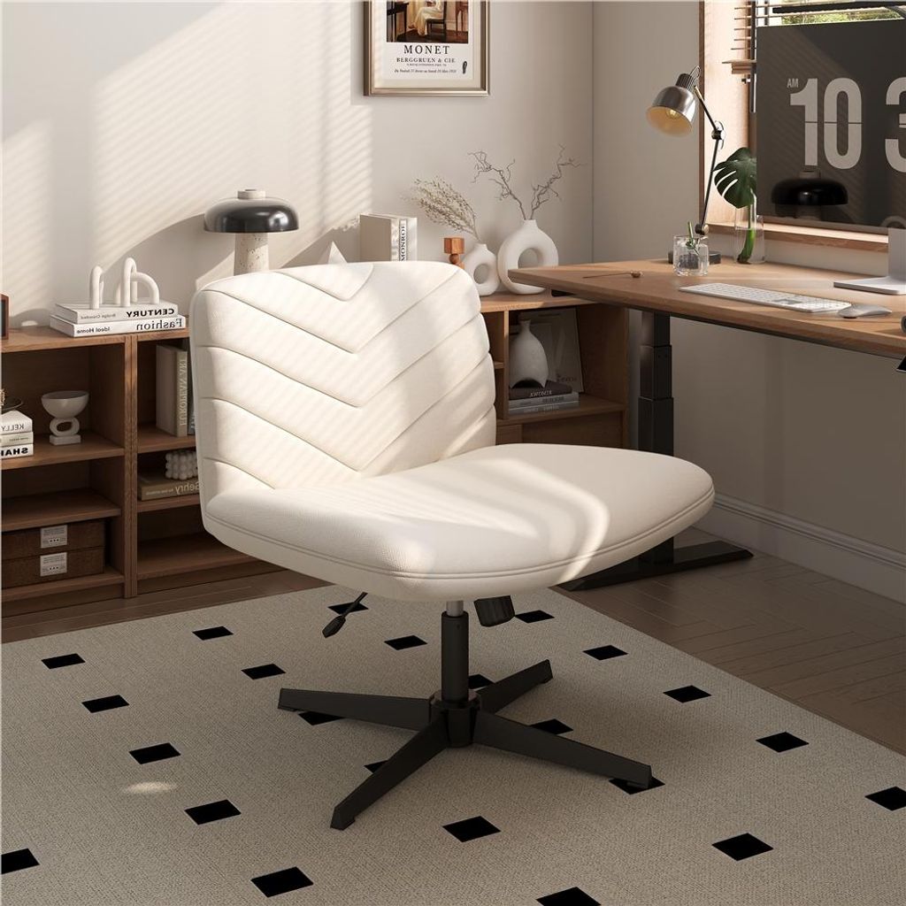 A modern home office setup with a beige office chair in the foreground, a wooden desk with a computer monitor, and bookshelves in the background.