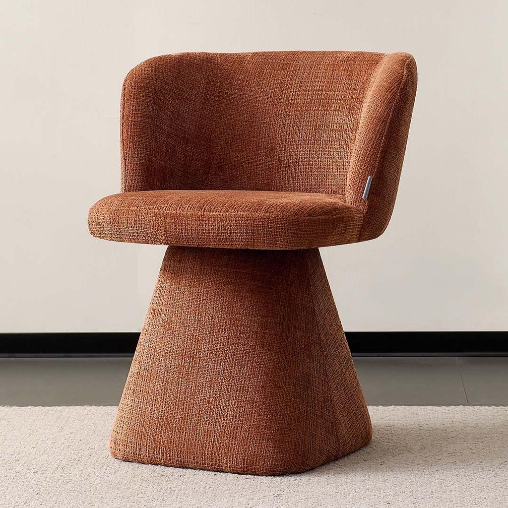 A single orange-brown upholstered swivel chair with a flared base sits on a light-colored rug.