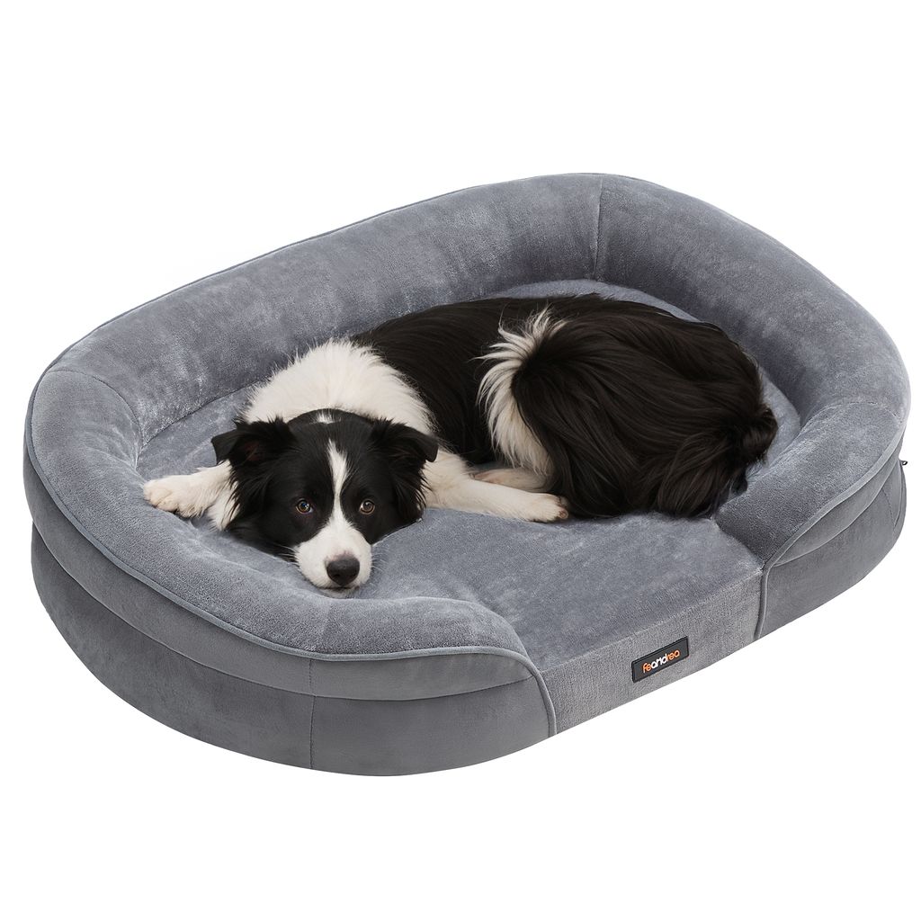 A border collie dog is lying on a gray dog bed.