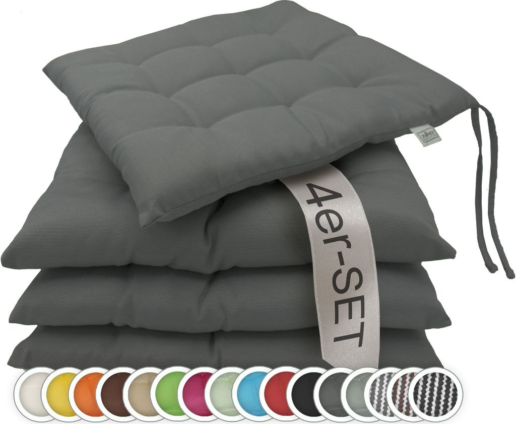 A stack of four dark gray seat cushions with a promotional band across them.
