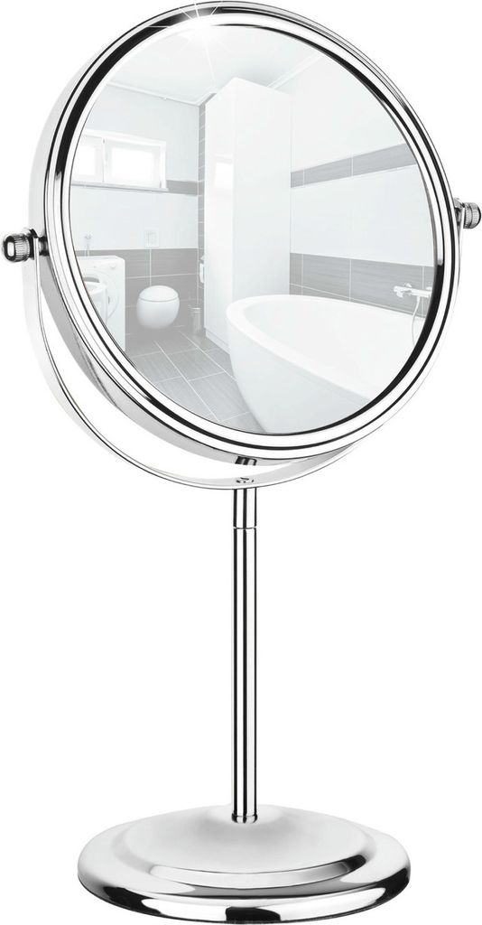 A silver-colored double-sided vanity mirror with a stand, reflecting a bathroom interior.