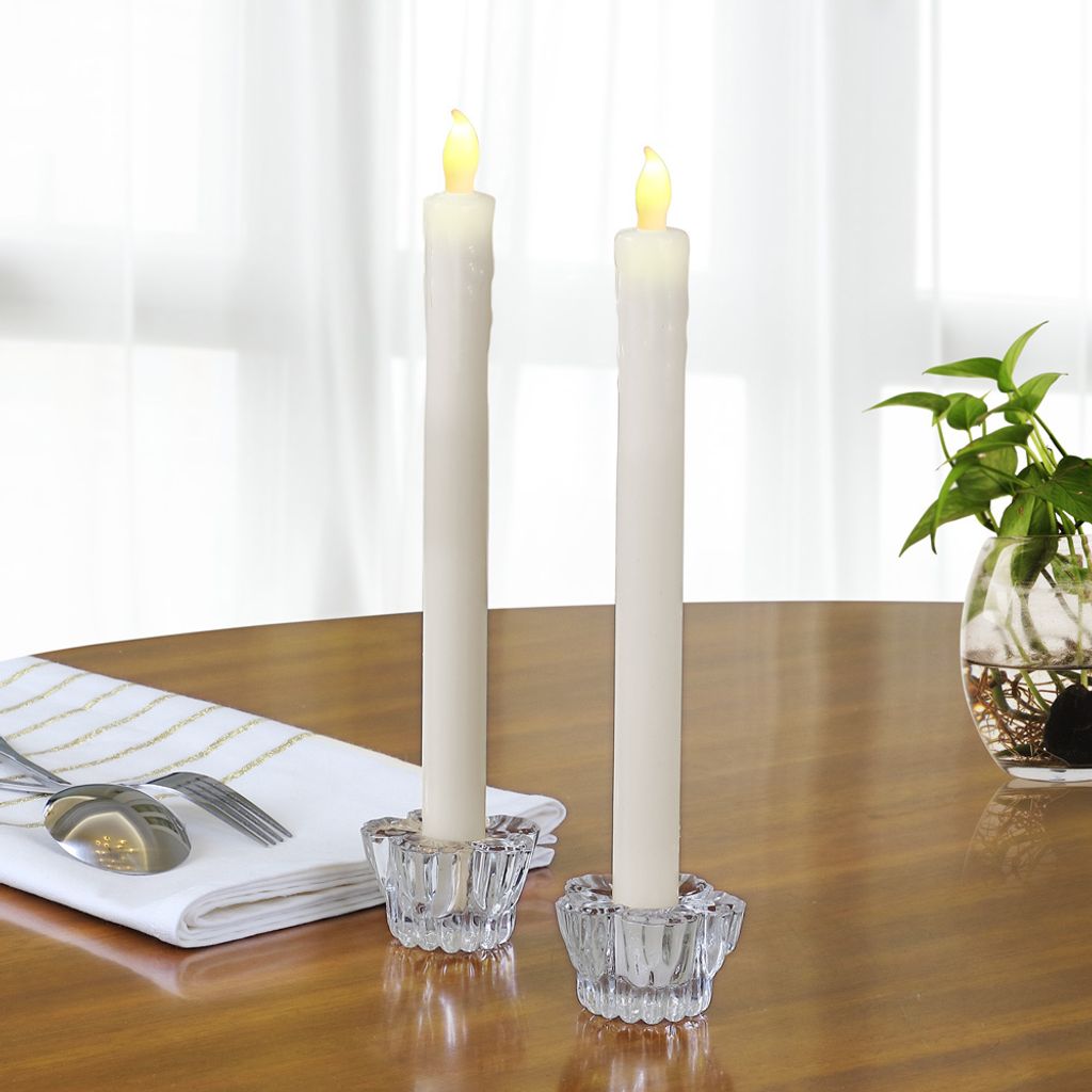 Two LED taper candles in glass candle holders on a wooden table.