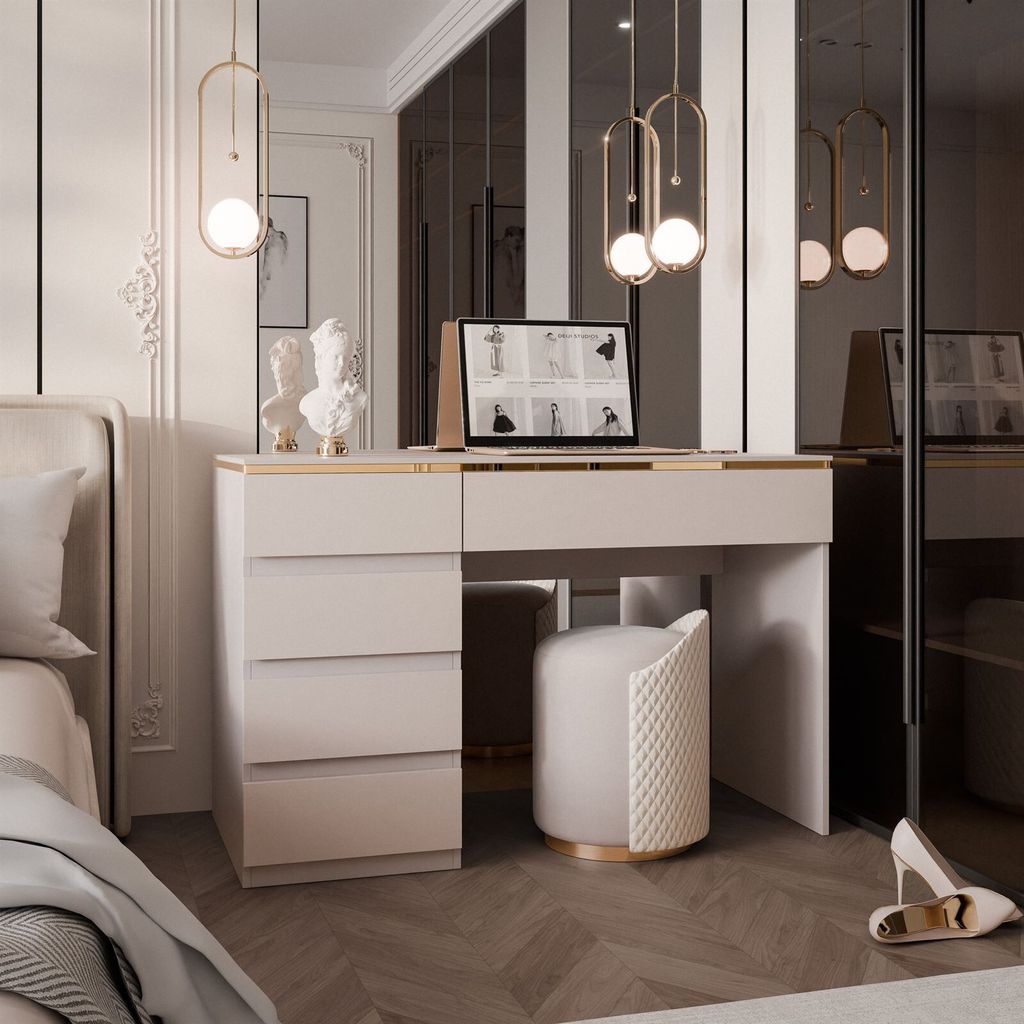 A bedroom vanity desk with drawers and a stool in a modern, luxurious setting. A laptop is open on the desk.