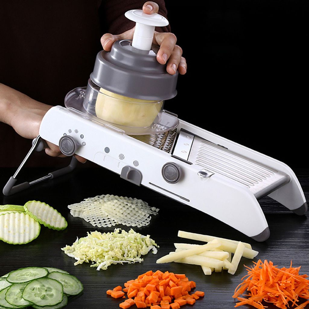 A person is using a multi-functional vegetable slicer to prepare food, with various chopped vegetables displayed around the slicer.