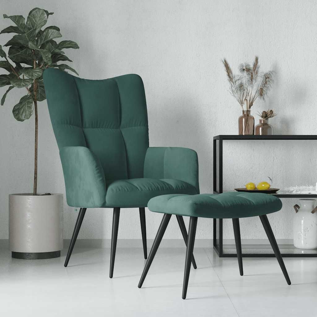 A dark green velvet armchair and ottoman are displayed in a minimalist room setting with a potted plant and a shelf with decorative items.