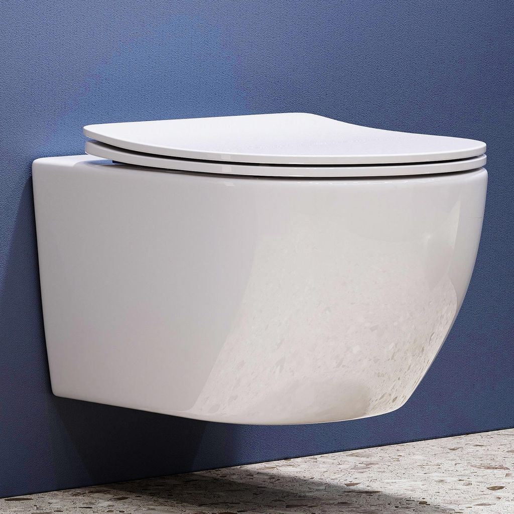 A white wall-mounted toilet with a closed lid is shown against a blue wall and a speckled gray floor.