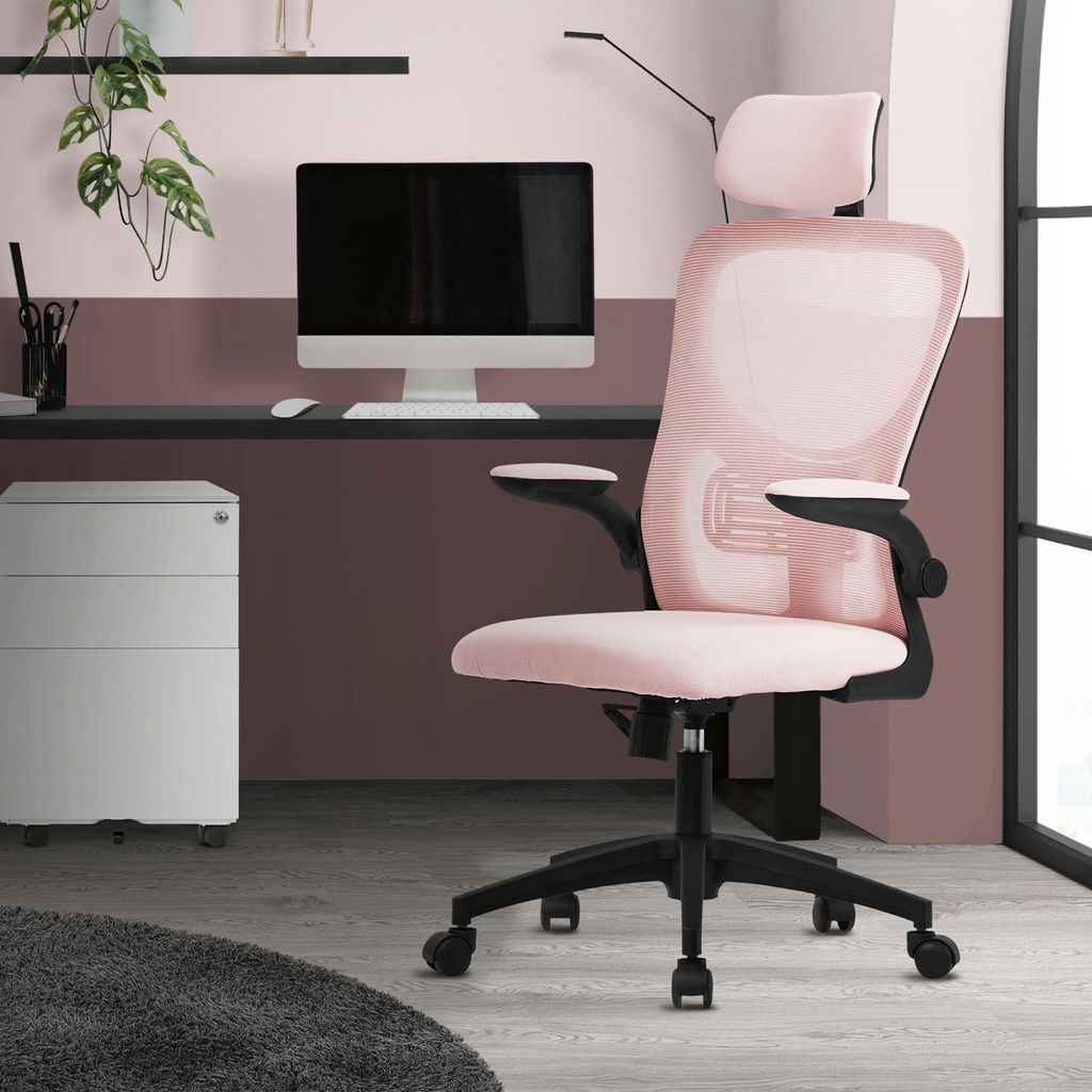 A pink ergonomic office chair is shown in a home office setting with a desk, computer, and filing cabinet.