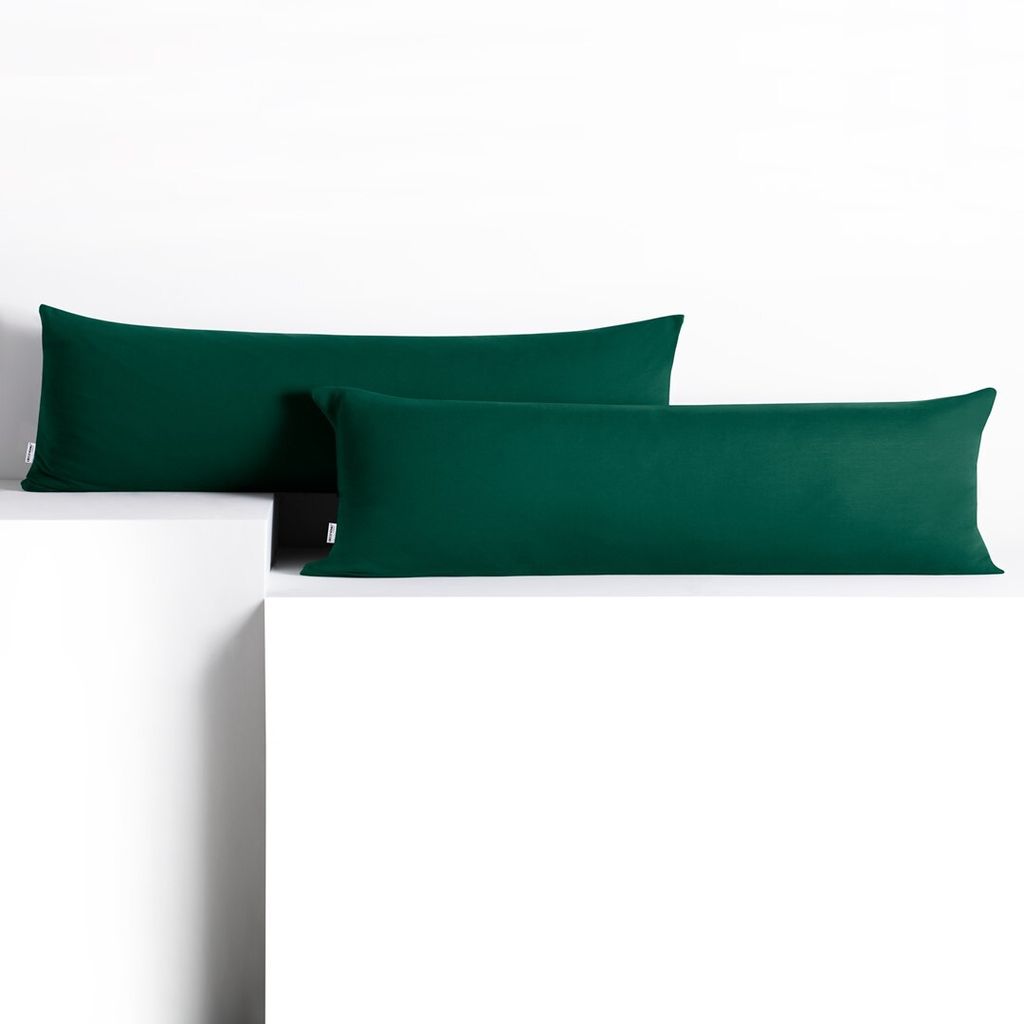 Two dark green body pillows are placed on white platforms against a white background.