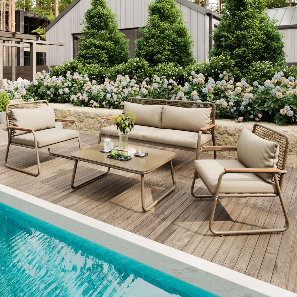 A patio furniture set is arranged on a wooden deck next to a swimming pool, with lush greenery and a house in the background.