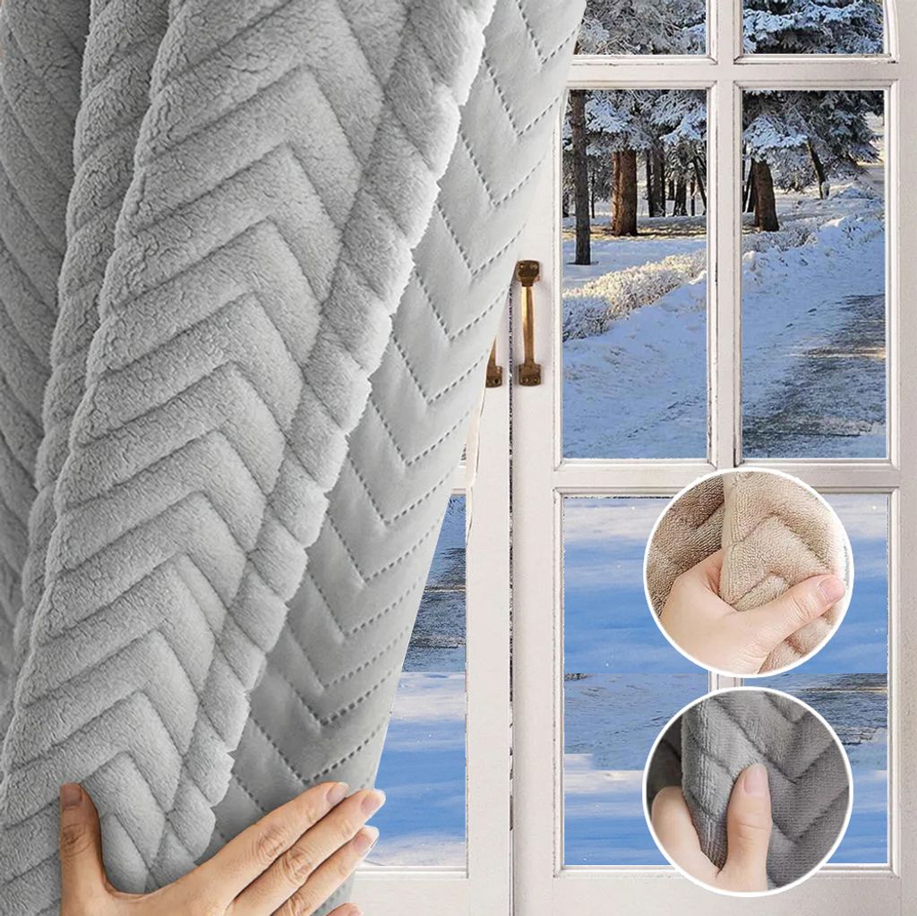 A hand is shown pulling back a gray, textured curtain to reveal a snowy outdoor scene through a window.