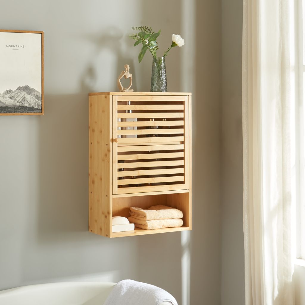A wooden bathroom cabinet mounted on a gray wall next to a window with sheer curtains.