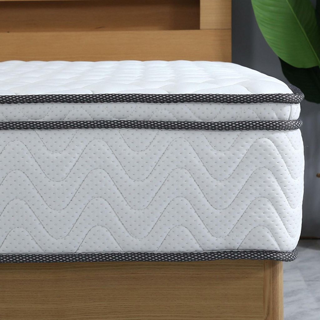 A close-up view of a mattress on a wooden bed frame.