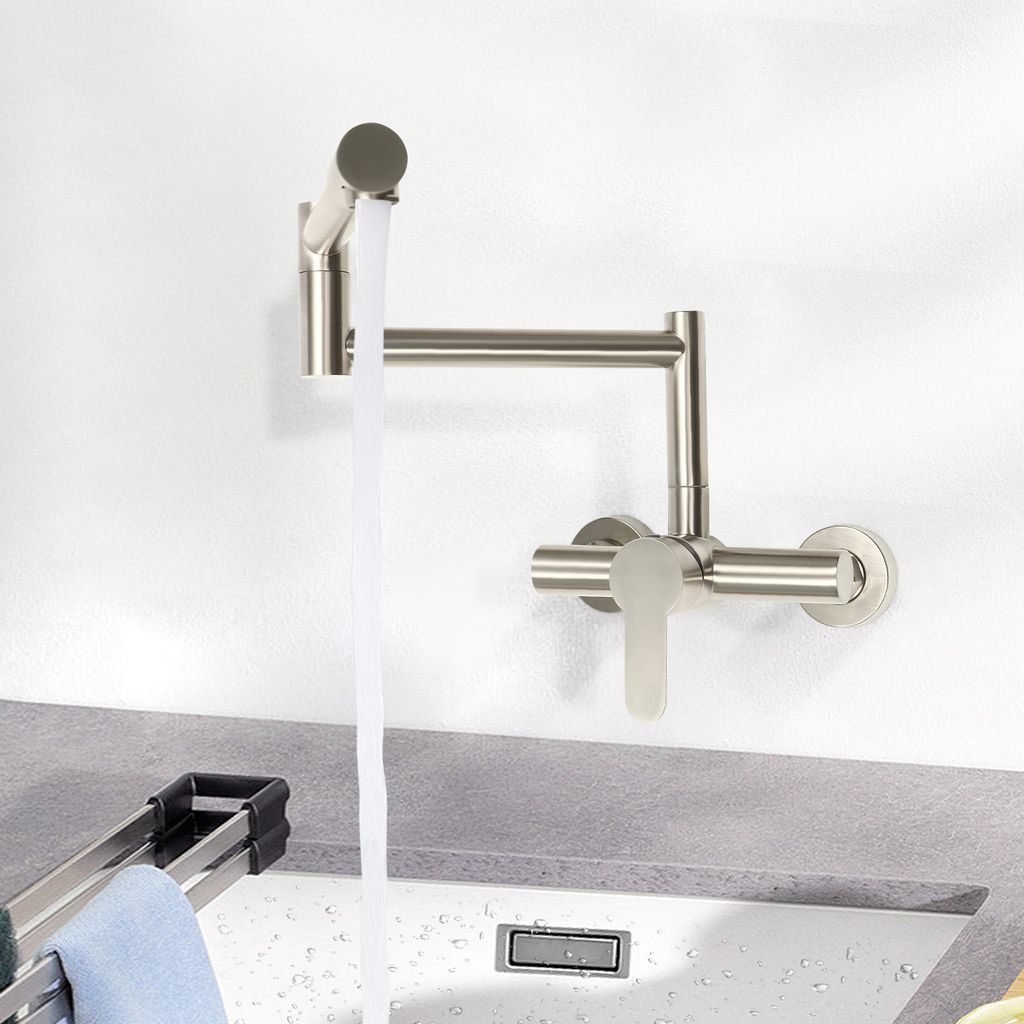 A wall-mounted kitchen faucet with water running into a sink.