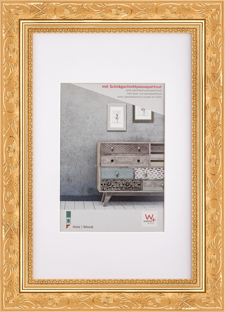 A gold-colored picture frame with a white mat, displaying a marketing image of a dresser.