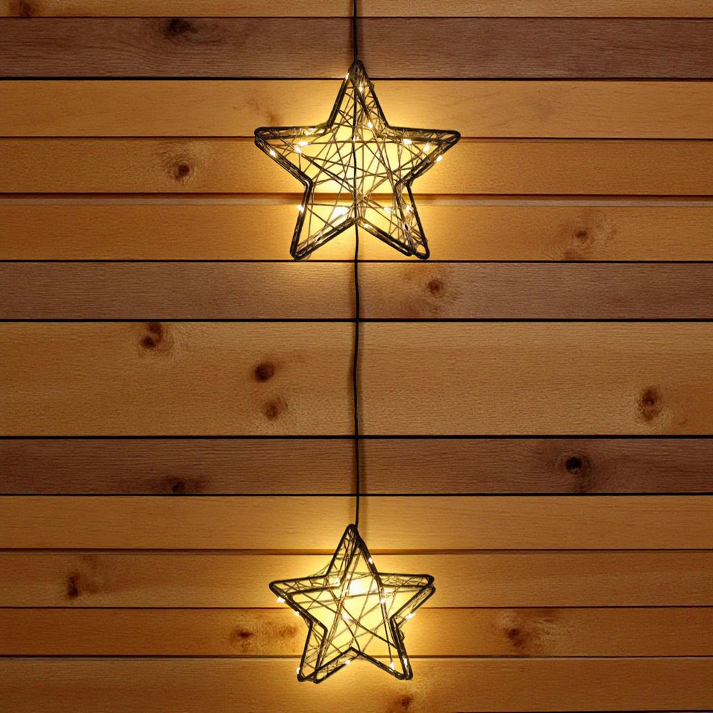 Two star-shaped string lights hang vertically against a wooden plank wall.