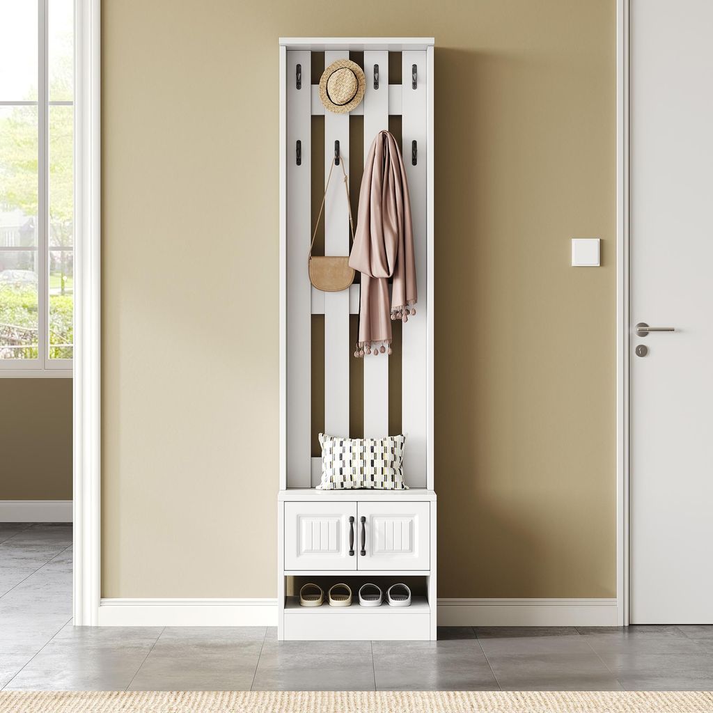 A white entryway organizer with hooks, a cabinet, and a shelf for shoes, set against a light beige wall and a gray floor.