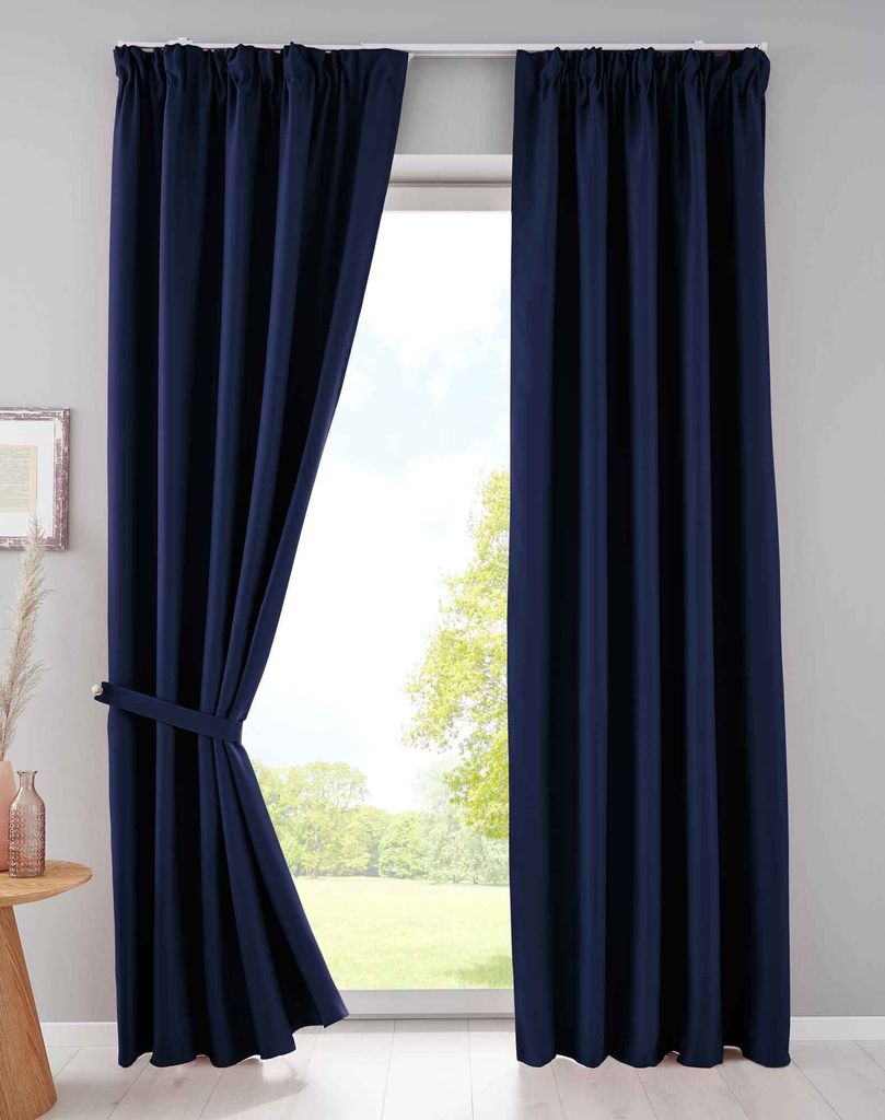 A pair of navy blue curtains are shown tied back on the left side, revealing a window with a view of trees and sky. The curtains are hung from a white rod.