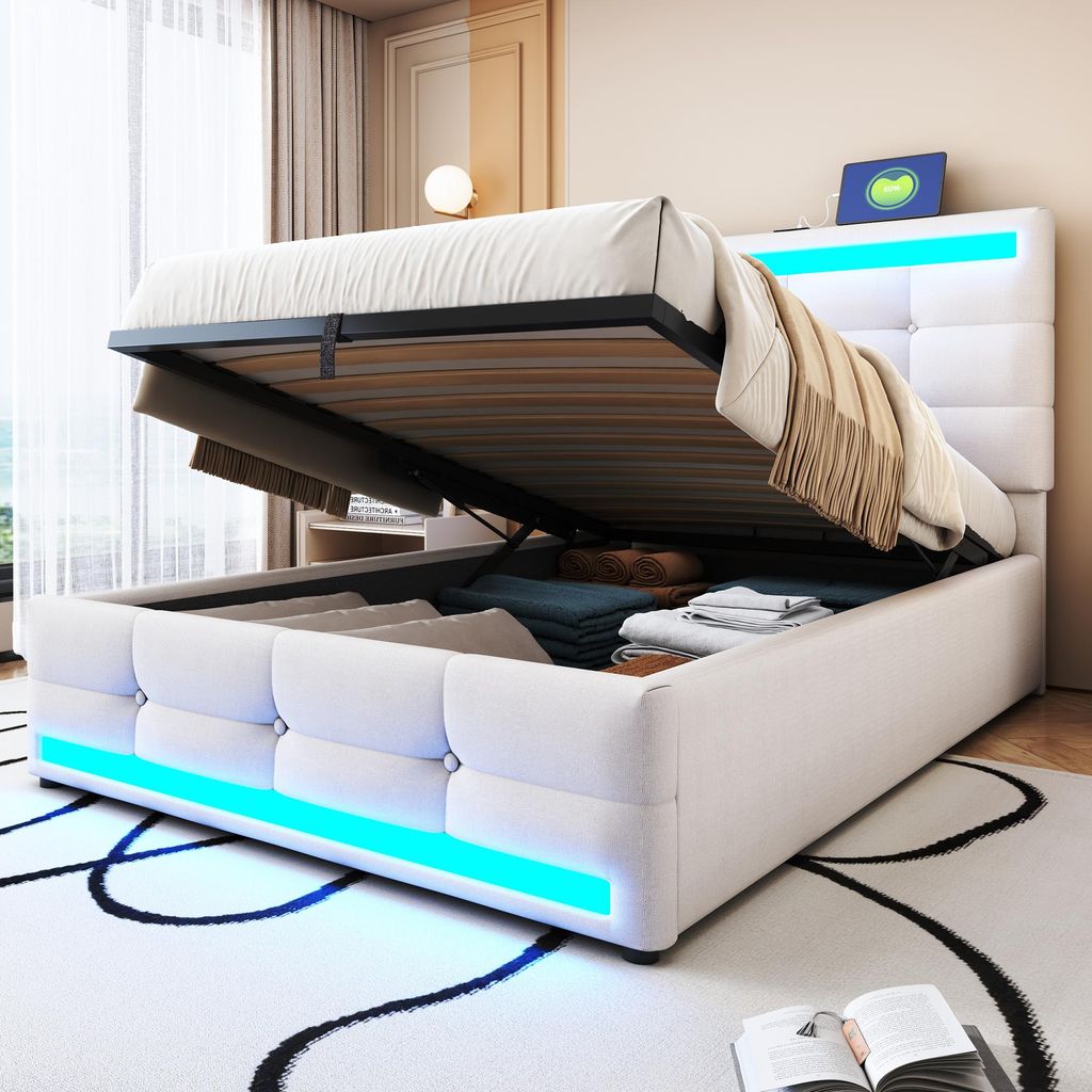 A white upholstered bed with storage is shown with the mattress lifted, revealing stored items. Blue LED lights illuminate the base of the bed.