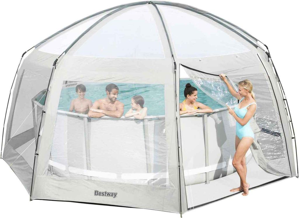 A family is enjoying themselves in an above-ground swimming pool covered by a large, transparent tent.