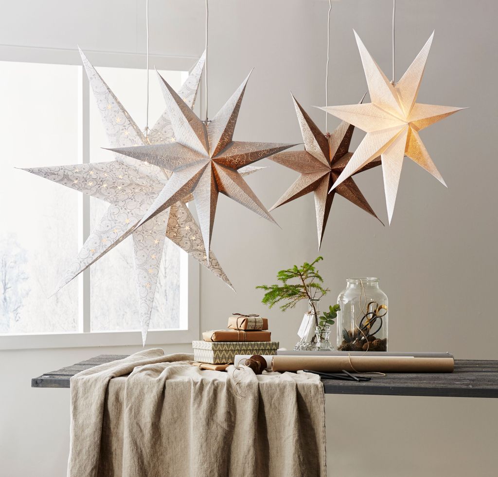A table set with gifts and decorations, featuring star-shaped paper lanterns hanging above.