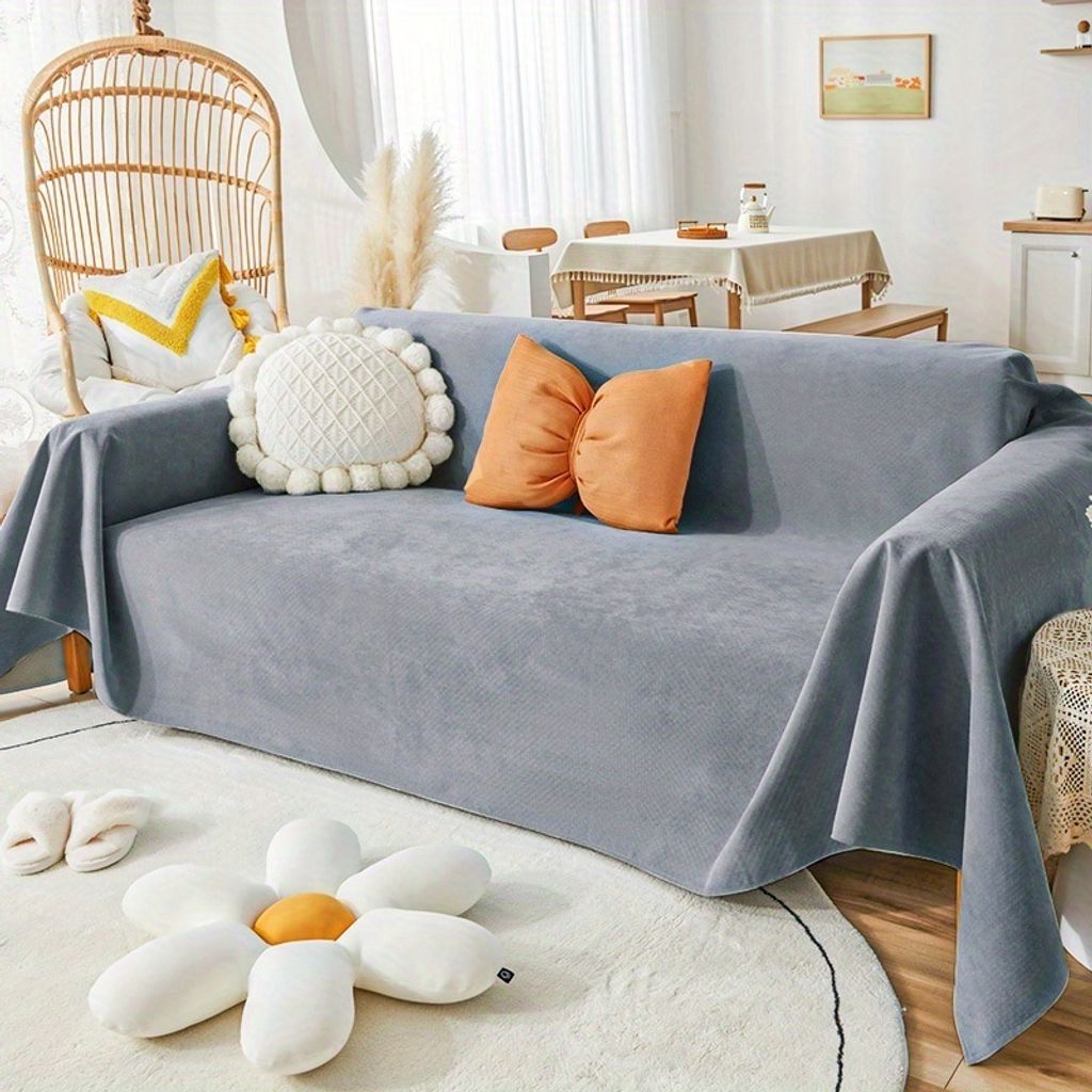 A living room scene with a sofa covered by a gray slipcover, decorated with pillows and a rug.