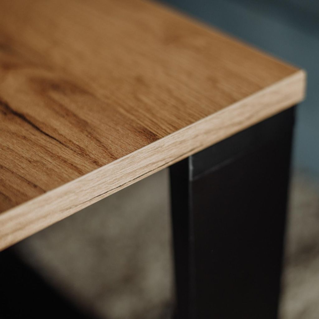 Close-up of a wooden tabletop with a black leg.
