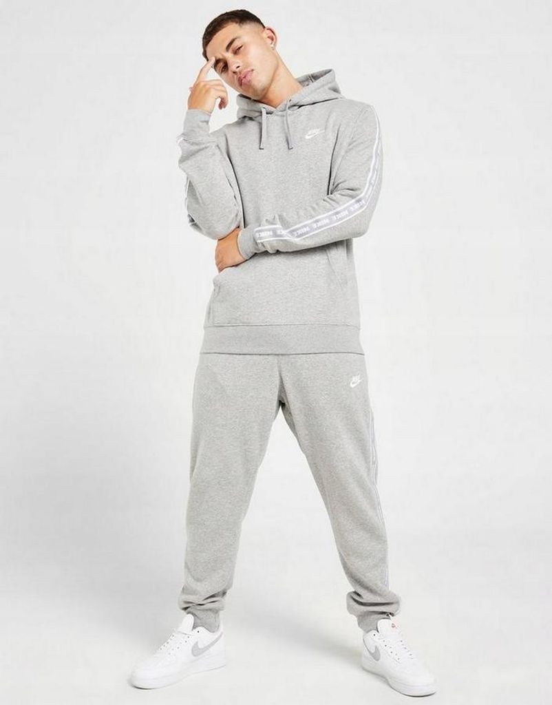 A man is posing in a grey Nike tracksuit.