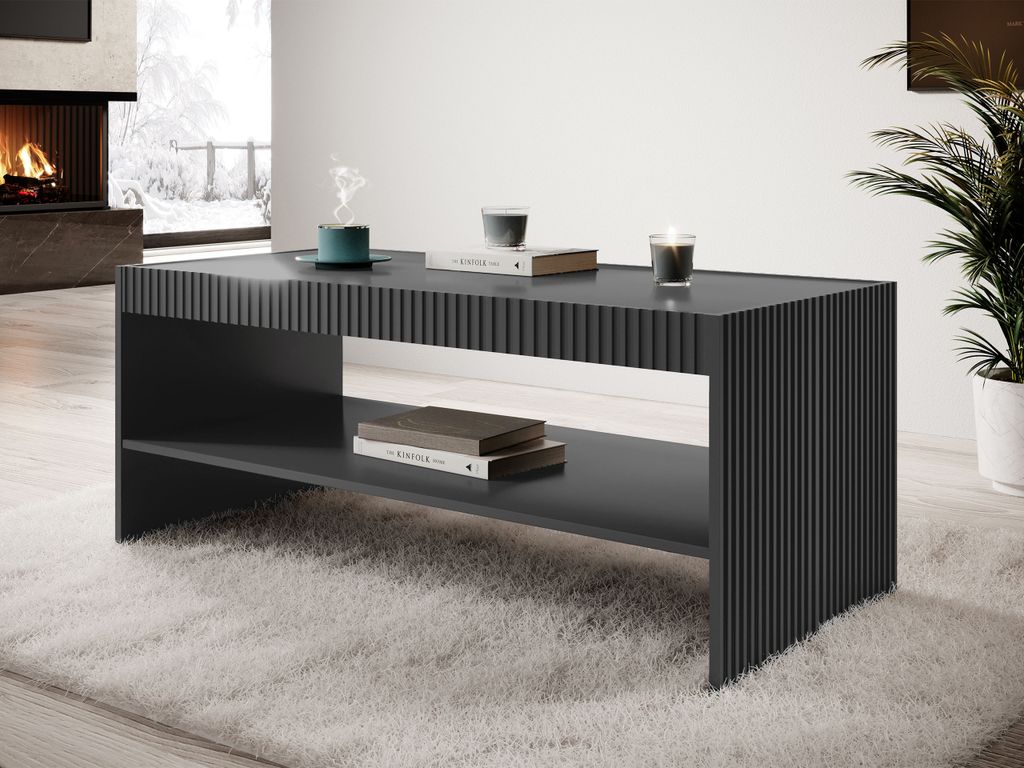 A modern living room with a fireplace, a large window with a winter view, and a plant. A dark gray coffee table with a ribbed design is placed on a fluffy white rug.